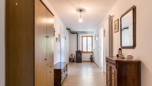 Um corredor com piso de madeira, um armário, um espelho e um lustre.