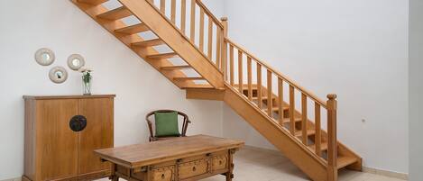 A staircase with wooden railings and a wooden table with drawers.