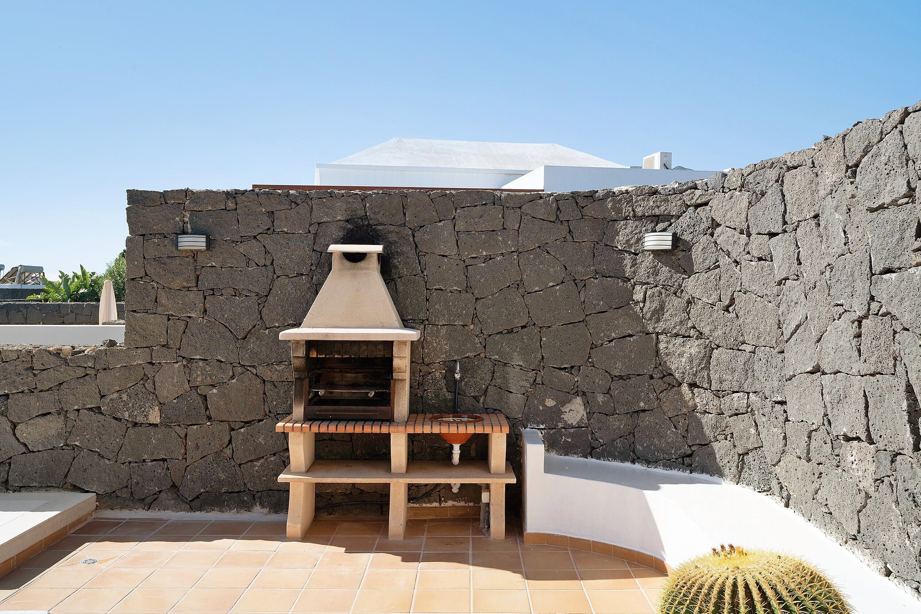 Un mur de pierres avec un barbecue et un cactus.