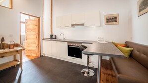 Eine moderne Küche mit weißen Schränken, einem eingebauten Ofen und einem Essbereich mit Tisch und Barhocker.