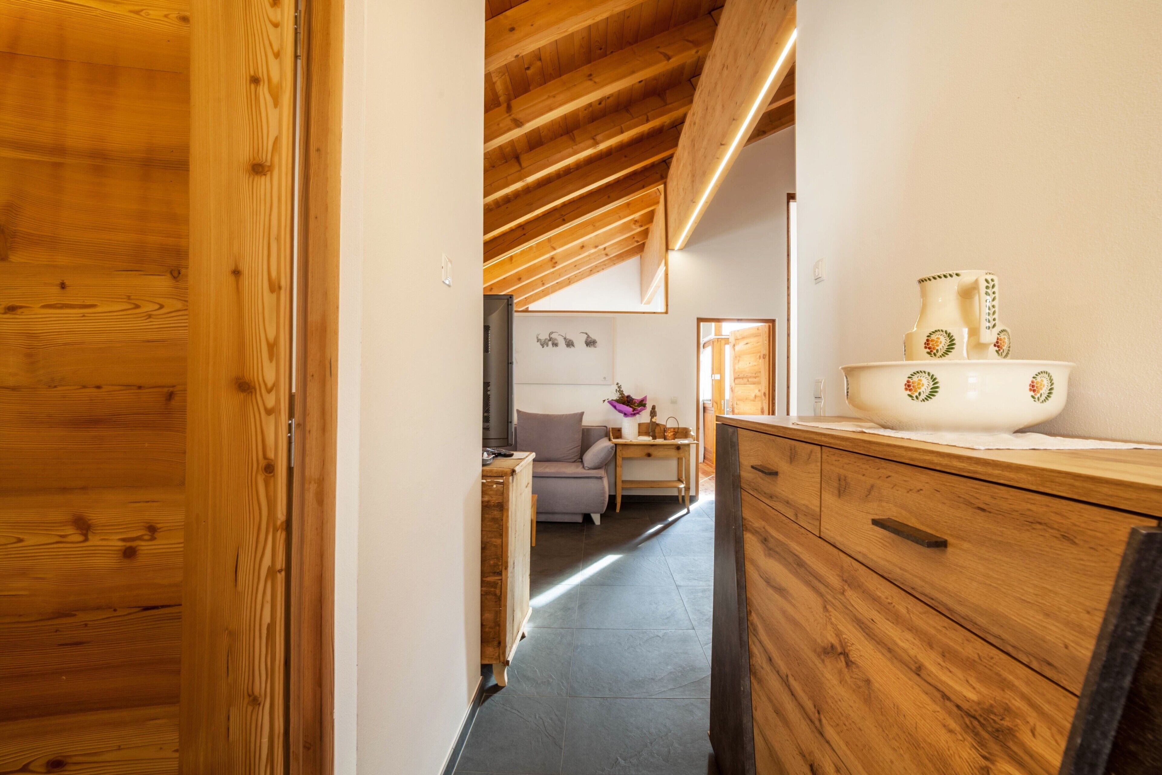 A wooden interior with a kitchen area, a sofa, and a dining table.