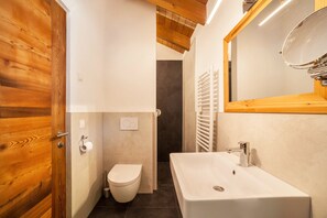 Ein Badezimmer mit Holztür, Toilette, Waschbecken und Spiegel.