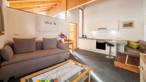 Ein modernes Wohnzimmer mit einer Couch, einem Couchtisch und einer Küchenzeile mit Schränken und einer Spüle.