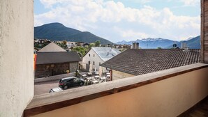 Blick vom Balkon auf eine Stadt mit Gebäuden, einem Berg und einem See.