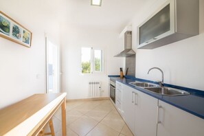 A kitchen with a blue countertop, stainless steel sink, and a built-in microwave.