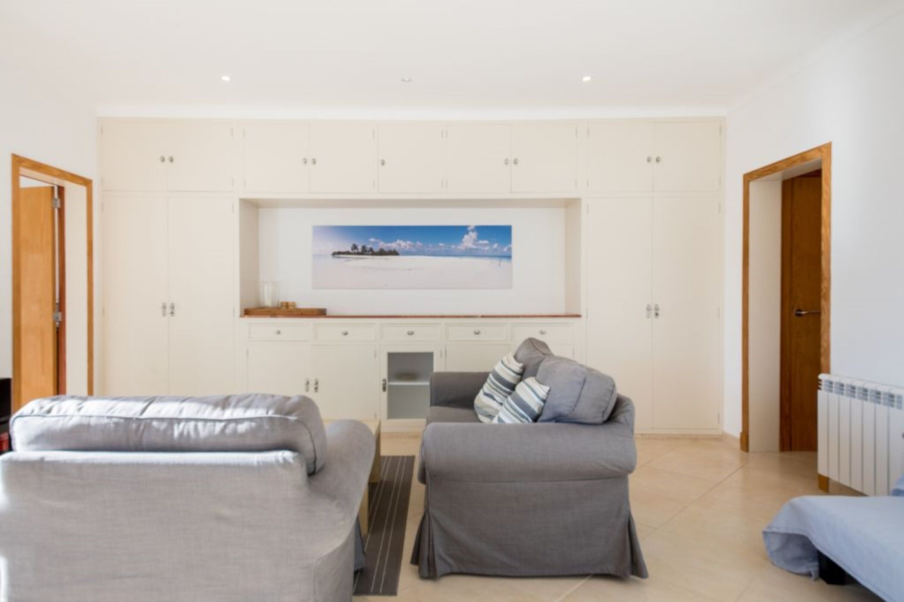 A modern living room with two sofas, a coffee table, and a flat-screen TV mounted on a white wall.