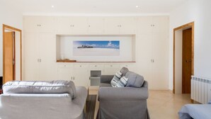 A modern living room with two sofas, a coffee table, and a flat-screen TV mounted on a white wall. - Holiday Apartment Ponent with Sea View, Mountain View, Balcony, Terrace & Pool (Puerto de Sóller)