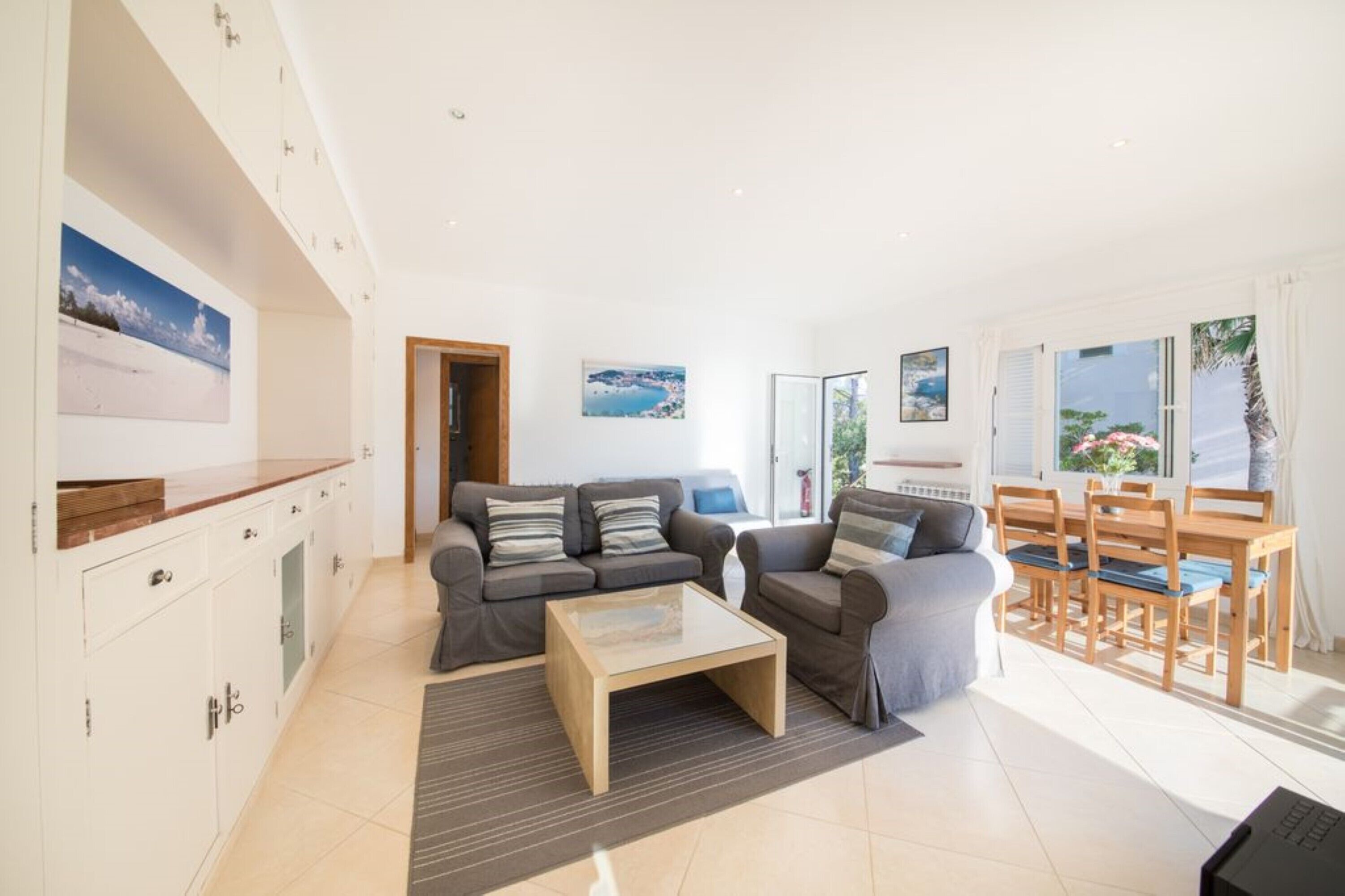 A modern living room with a sofa set, a coffee table, and a dining area with wooden chairs and a table.