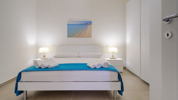 Une chambre d’hôtel avec un lit, deux lampes de chevet, un tableau et une vue sur la plage.