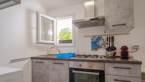 Une cuisine avec une fenêtre, une cuisinière, un four et un lave-linge.