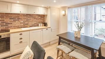 A kitchen with white cabinets, a brick backsplash, and a dining area with a table and chairs.