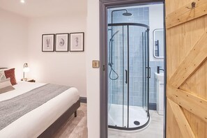 A bedroom with a bed, bedside table, lamp, and framed pictures on the wall. - Host & Stay | Grumbles Cottage (Whitby)
