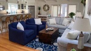 A spacious living room with a large sofa, a coffee table, and a dining area with chairs. -  3 Ensuite Bedrooms - In-town Gem - Walk Everywhere - Sleeps 12 - Private Drive (Rehoboth Beach)