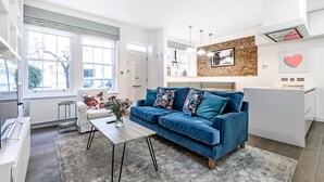 Un salon moderne avec un canapé bleu, une table basse et une vue sur l’extérieur.