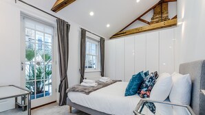 Une chambre moderne avec un lit, une table de chevet, une fenêtre avec des rideaux et une vue sur l’extérieur.