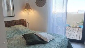 A bedroom with a bed, a bedside lamp, and a view of the outdoors.