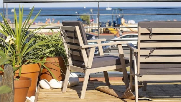 A balcony with two wooden chairs, a small table, and potted plants.