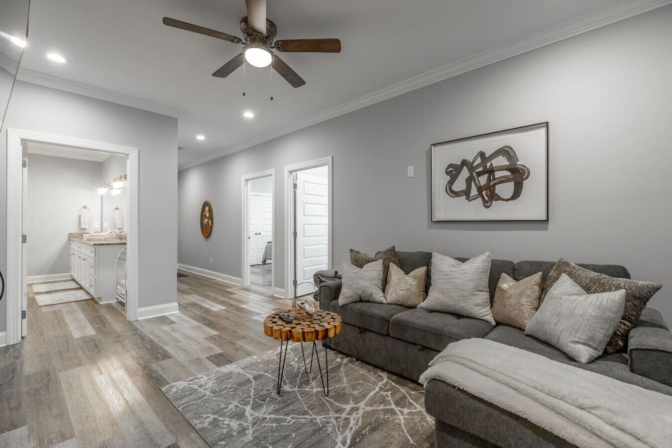 A modern living room with a grey sofa, a coffee table, and a ceiling fan.
