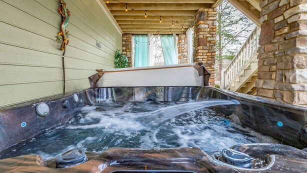 Un jacuzzi con panel de control, rodeado de paredes de piedra y vigas de madera.