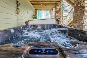 A hot tub with a control panel, surrounded by stone walls and wooden beams.