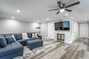 Relax in this inviting living room with a sectional sofa, ottoman, and patterned rug on hardwood floors.