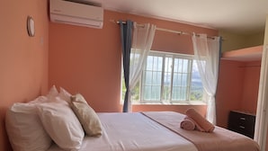 Une chambre avec un lit, une fenêtre avec des rideaux et un climatiseur fixé au mur.
