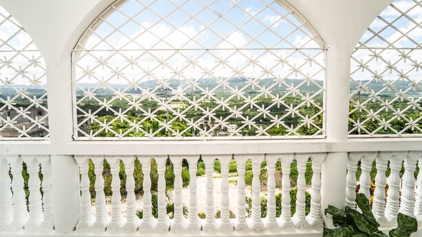 Een wit balkon met uitzicht op groene velden en gebouwen in de verte.
