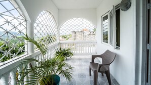 Een balkon met witte hekwerk, een bloempot en een stoel.