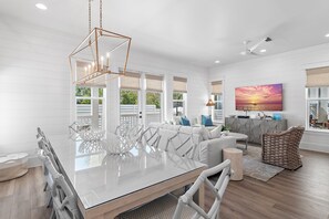 Un salón amplio con una gran mesa de comedor de vidrio, sofás blancos y un ventanal con vistas.