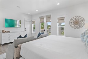 Un dormitorio amplio con una cama grande, un aparador, un televisor y un balcón con vistas.
