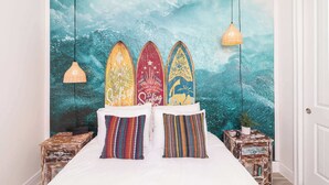 A bed with three surfboards on the headboard, a lamp, and a small table with a plant. - Rum Runners and Margaritas (Kissimmee)