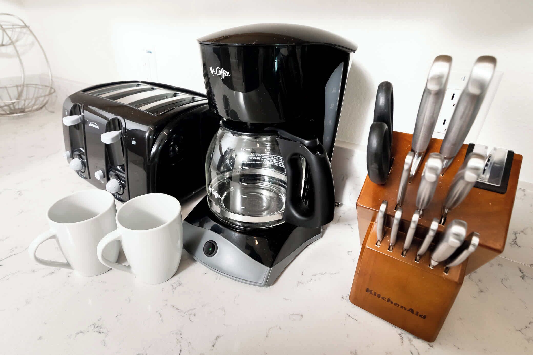 A kitchen with a coffee maker, toaster, and knife block.