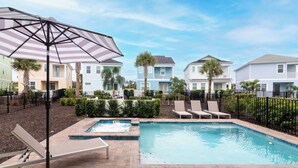 A swimming pool with lounge chairs and an umbrella, surrounded by a brick patio and a fence. - Rum Runners and Margaritas (Kissimmee)