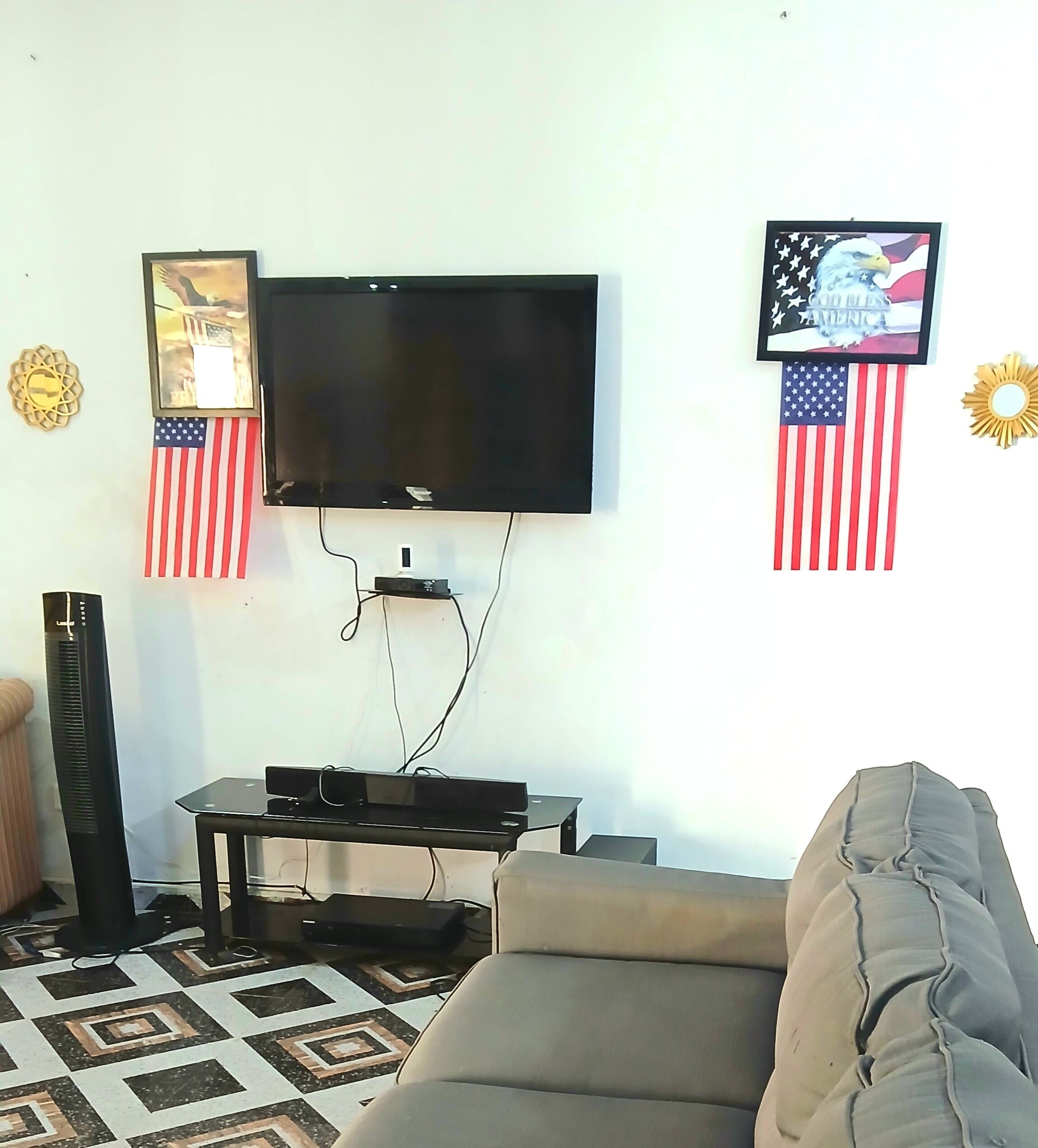 Una sala de estar con una televisión de pantalla plana montada en la pared, un sofá y una mesa de centro.