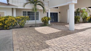 A two-story house with a covered patio, a blue door, and a small palm tree.