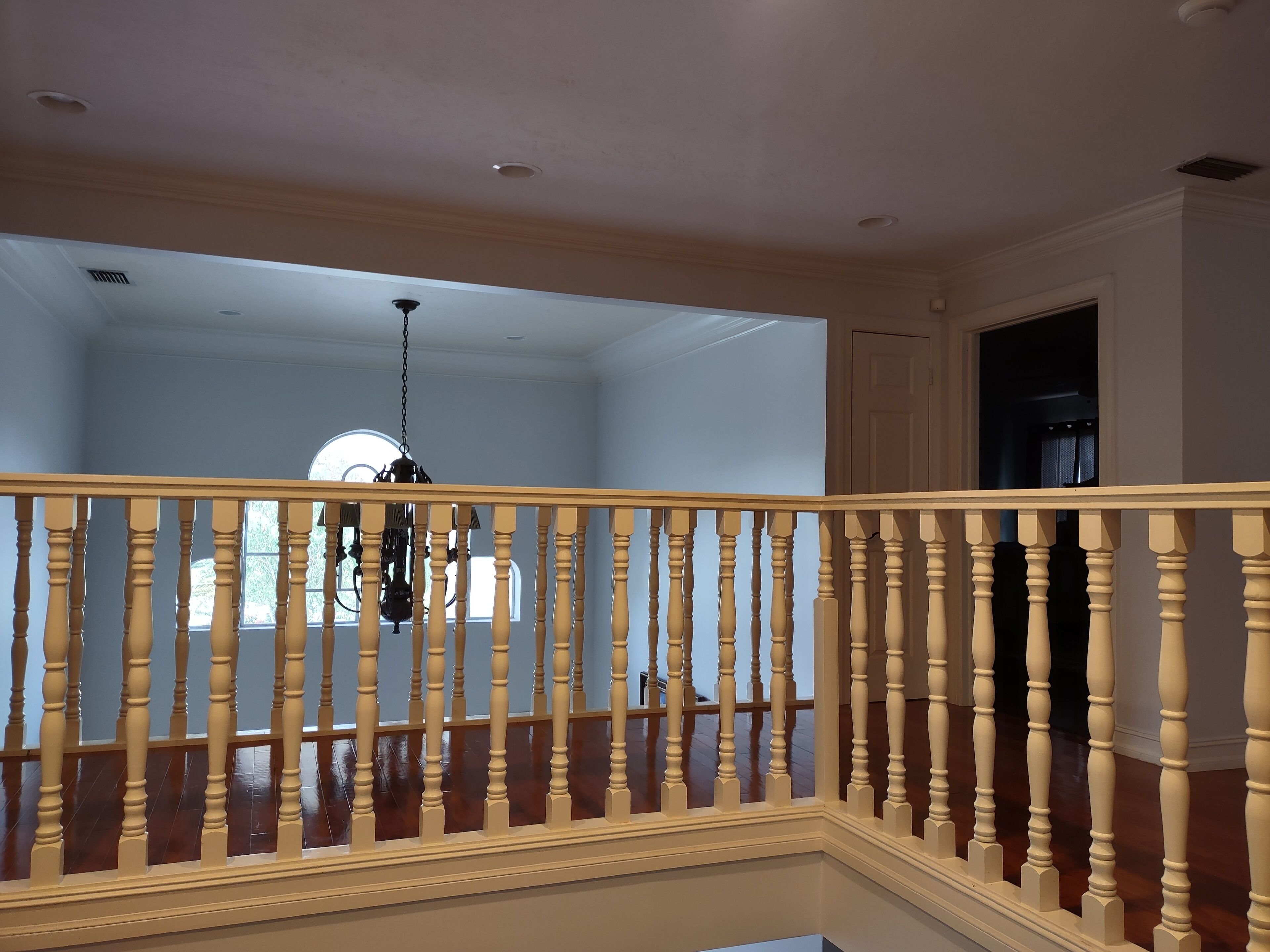 Un escalier en bois avec une balustrade blanche menant à une pièce dotée d’un ventilateur de plafond et d’une fenêtre.