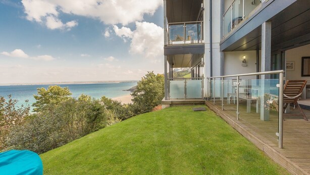 A modern building with a balcony overlooking a beach.