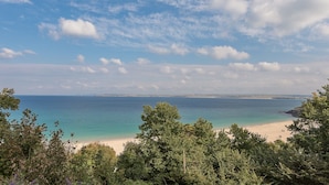 A coastal landscape with a beach, trees, and a clear sky.