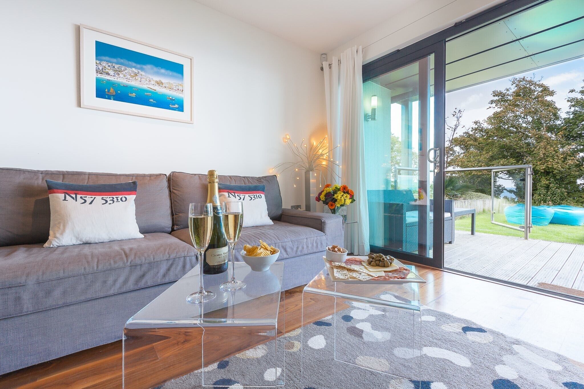 Ein modernes Wohnzimmer mit einer Couch, einem Glastisch und Blick ins Freie.