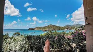 A balcony with a view of a coastal area, including boats and a mountainous landscape. - STARLIGHT: GORGEOUS VIEWS OF THE BEACH, FORT BERKLEY & MONTSERRAT (English Harbour)