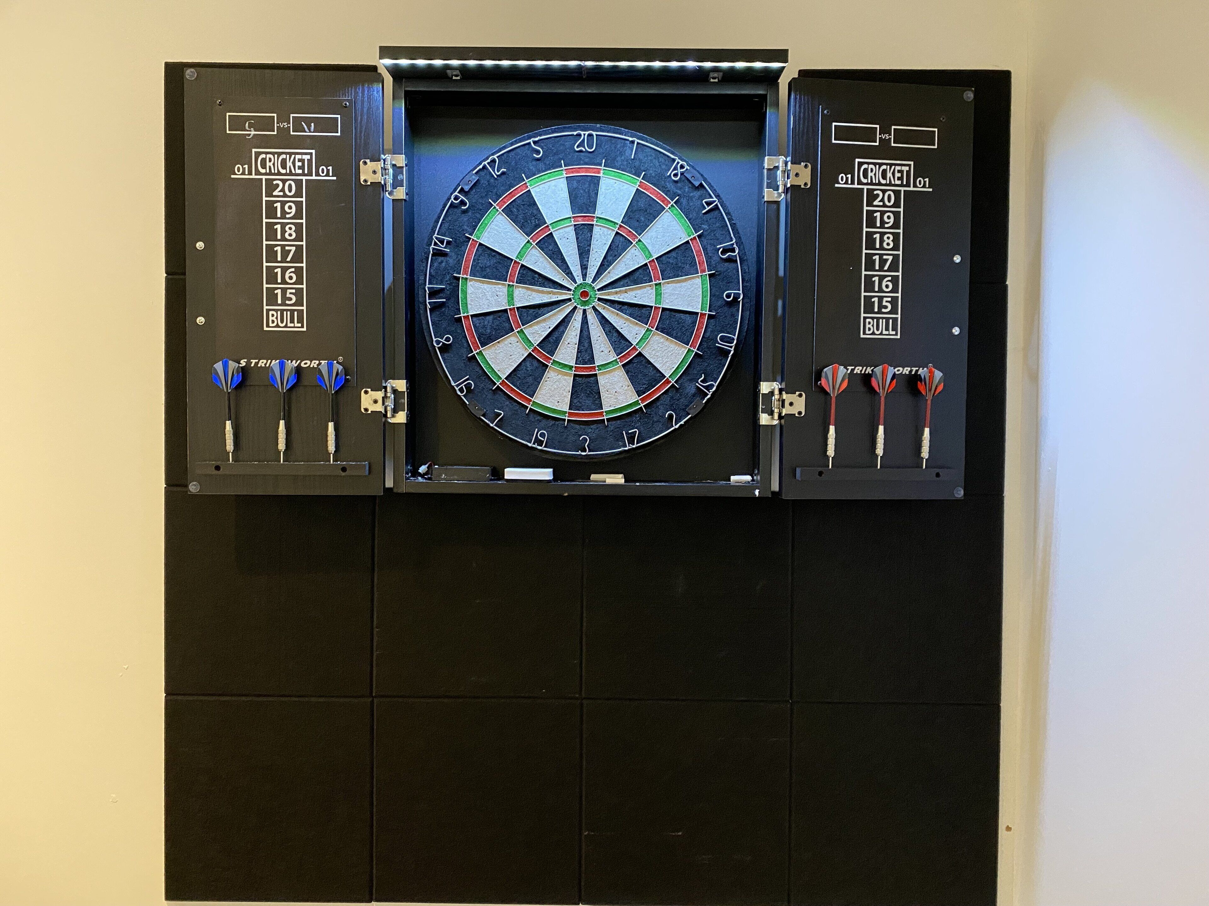 A dartboard mounted on a wall with a scoreboard on either side.