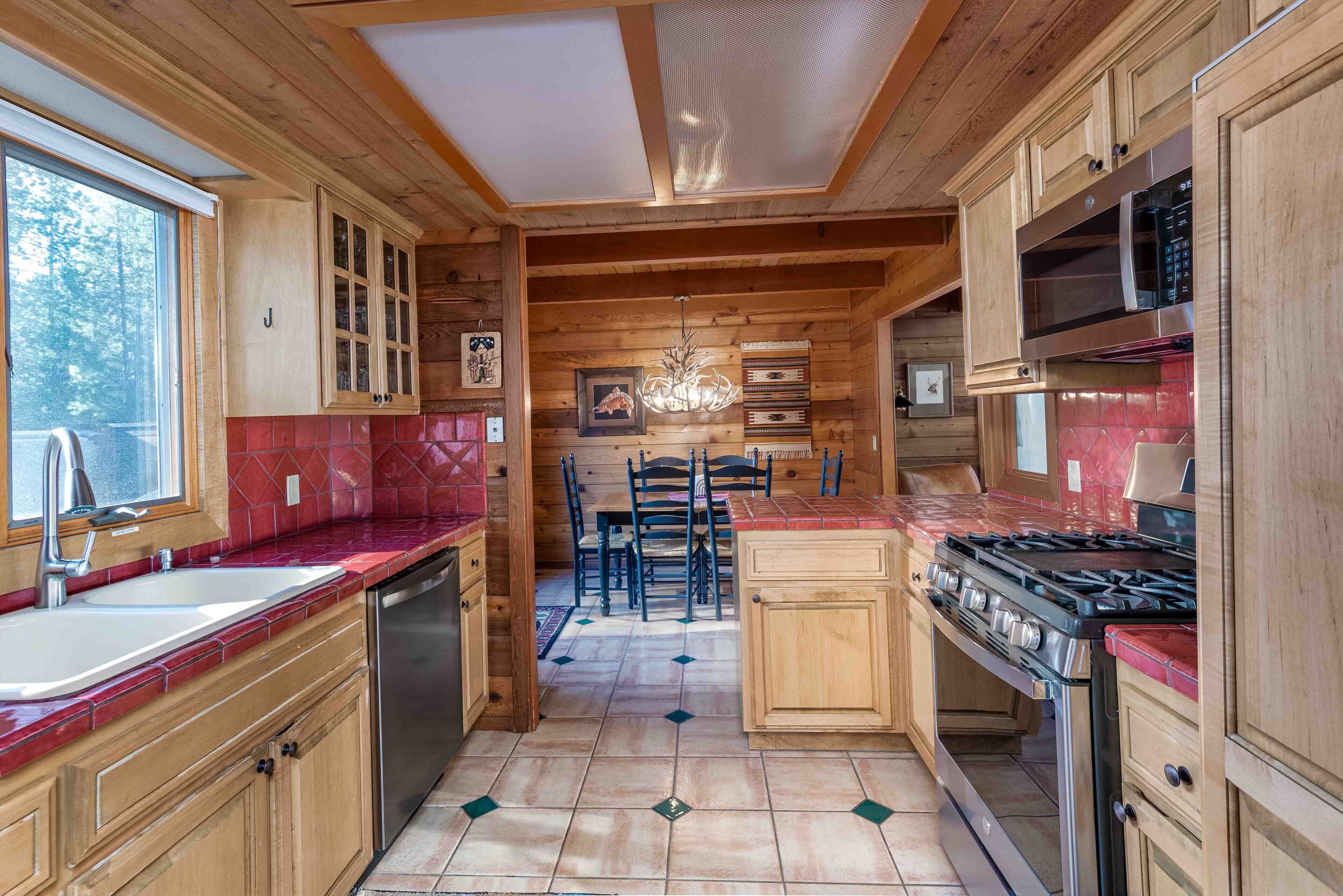 Une cuisine rustique, aménagée dans une cabane en bois, avec un îlot central, une cuisinière et un évier.