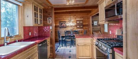 Une cuisine rustique, aménagée dans une cabane en bois, avec un îlot central, une cuisinière et un évier.