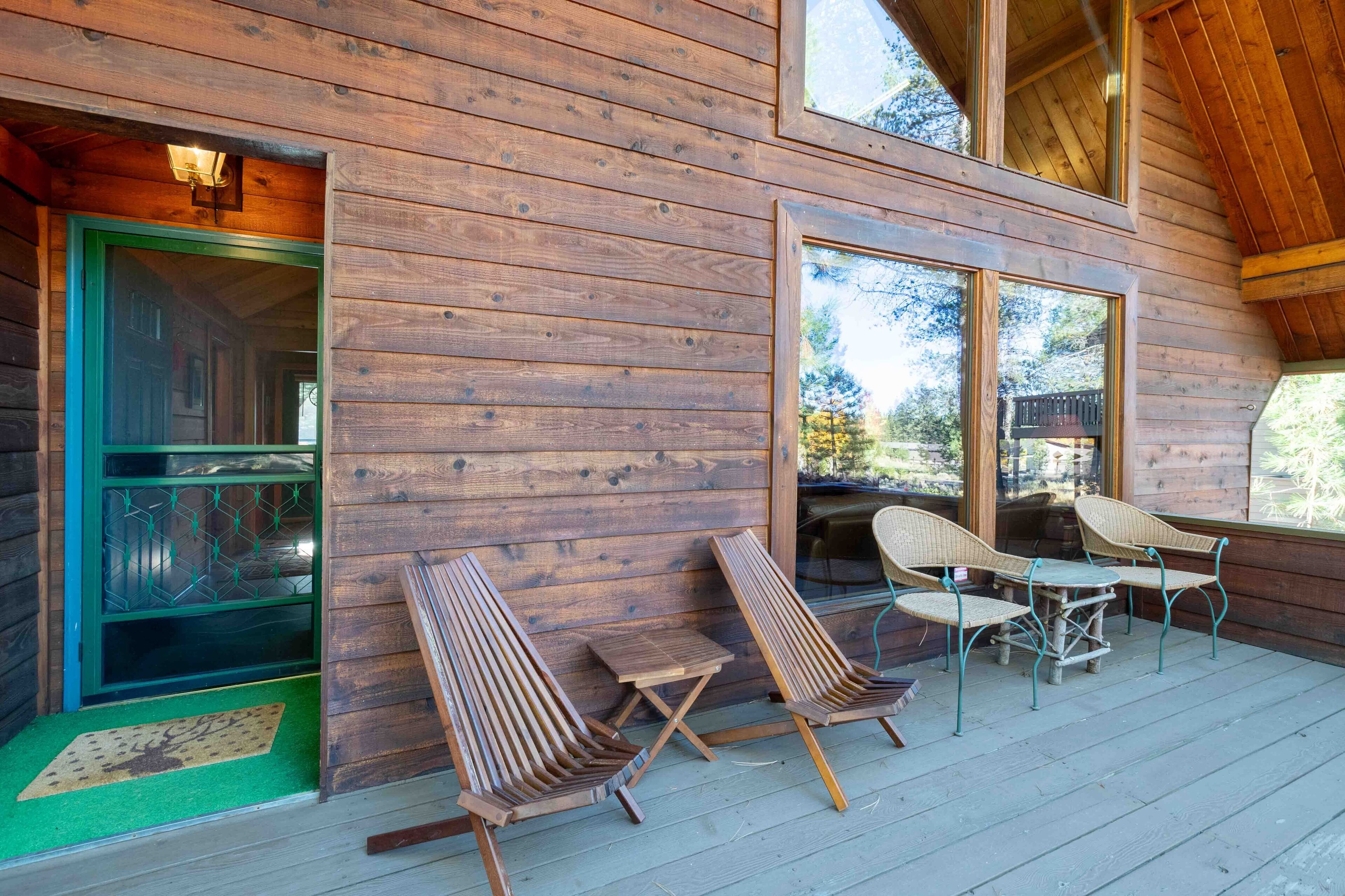 Une cabane en bois dotée d’une véranda, d’une porte-fenêtre coulissante et de meubles pour s’asseoir à l’extérieur.