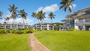 A resort with multiple-story buildings, palm trees, and a well-maintained lawn. - Poipu Sands 411 By Parrish Kauai: Private & end unit (Koloa)
