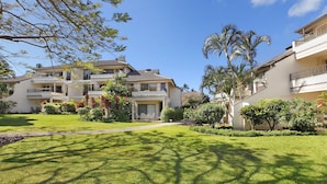 A two-story residential building with a balcony, surrounded by well-maintained lawns and tropical plants. - Kahala 822 By Parrish Kauai - AC and 1 level (Koloa)