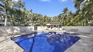 A swimming pool with lounge chairs and a covered seating area, surrounded by palm trees. - Kahala 822 By Parrish Kauai - AC and 1 level (Koloa)