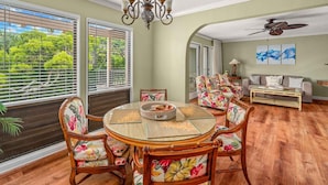 A dining area with a round table, floral chairs, and a ceiling fan. - Kahala 822 By Parrish Kauai - AC and 1 level (Koloa)