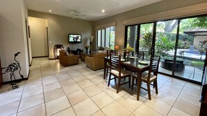 A spacious living area with a dining table set for four, surrounded by wicker furniture and a television mounted on the wall. - 2 BR Condo Centrally Located in Playas del Coco (Playas del Coco)