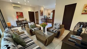 A living room with a sofa set, two armchairs, a coffee table, and a dining area with a table and chairs. - 2 BR Condo Centrally Located in Playas del Coco (Playas del Coco)